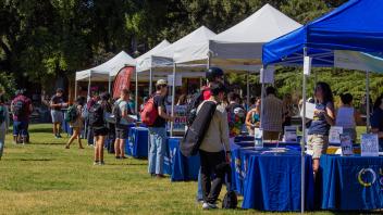 A diverse group of individuals gathered around a tent, engaged in conversation and enjoying the outdoor setting.