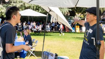 Photo of students gathered around a tabling getting information about global learning opportunities. They are outdoor at the Global Learning Fair on the UC Davis campus.