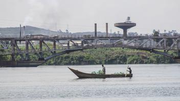 A boat on the river. There is a bridge in the background.