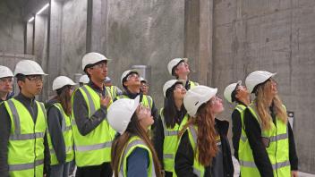 Students in a lab in Iceland--wearing hard hats and bright green vest--looking up off camera