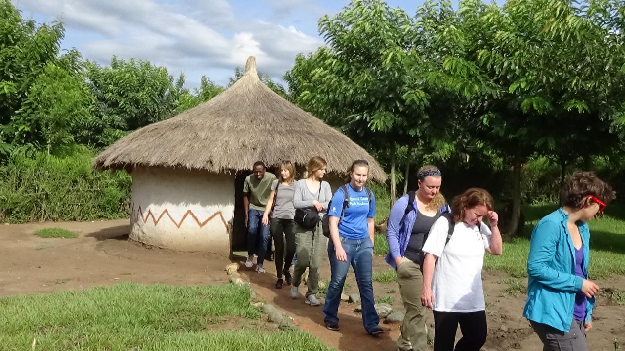 A group photos with a hut structure in the background.