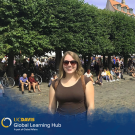 Photo of a student standing in a plaza in front of a crowd of people