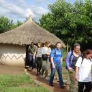 A group photos with a hut structure in the background.