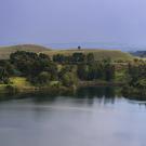 image of a lake in Uganda surrounded by greenery and mountains 