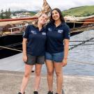 Two students smiling on a dock beside a ship named "Oosterschelde."