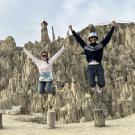 Three student in a large canyon. The all jump in the air at the same time and the photo captures them high in the air, smiling.