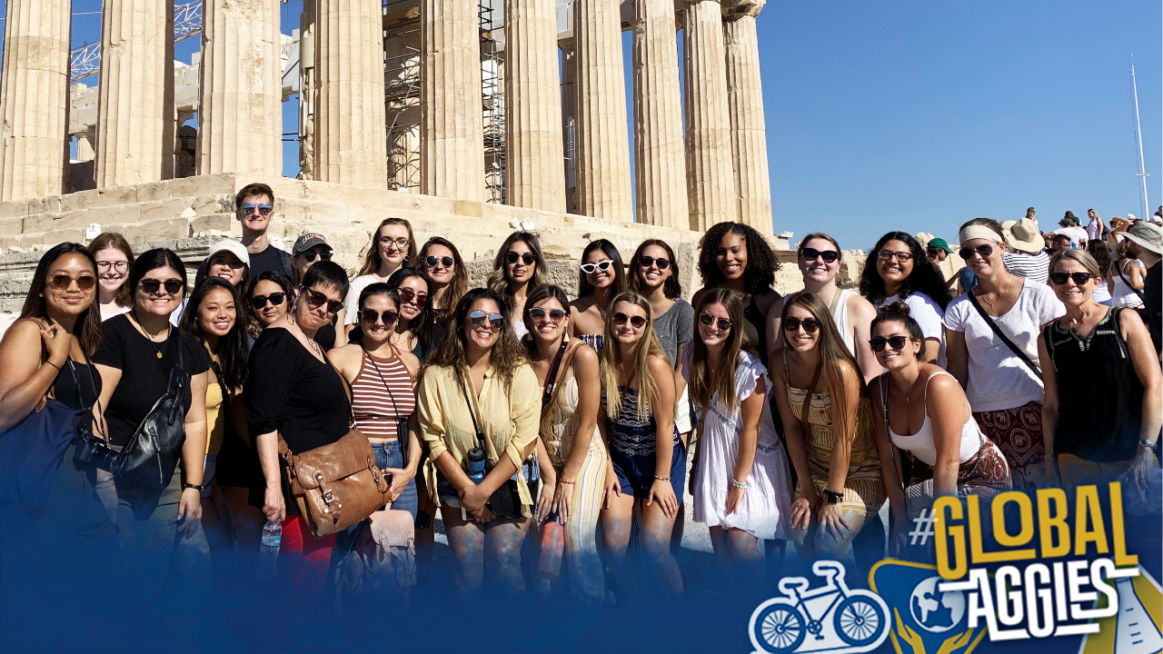 Students posing in front of ancient Greek temple columns on a sunny day, Global Aggies logo