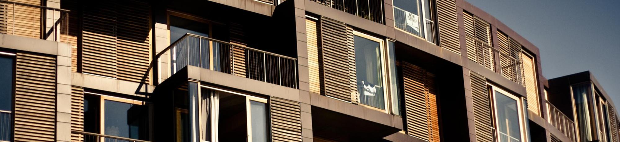 Modern apartment building with wooden facades and numerous balconies under a clear sky.
